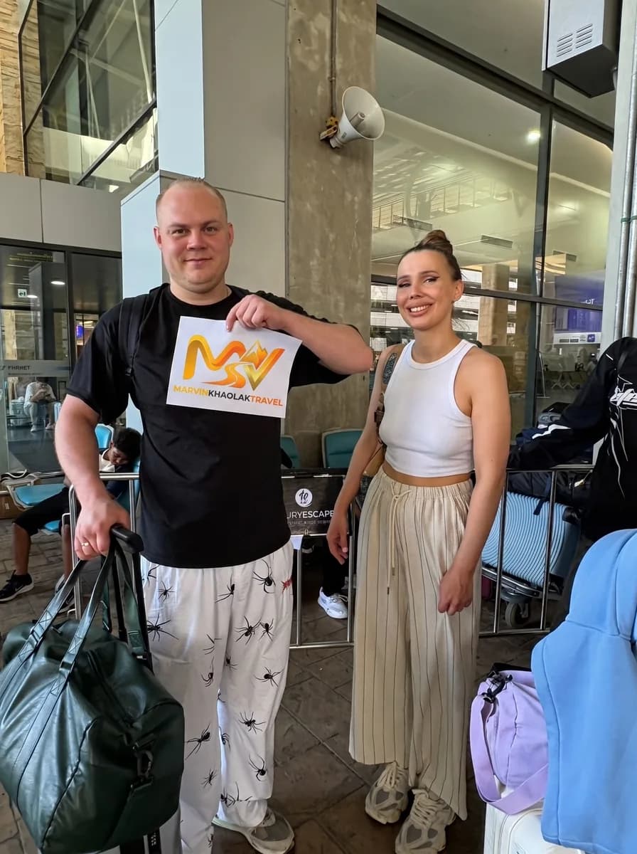 Couple with their bags at Phuket Airport arrivals before the drive to Khao Lak